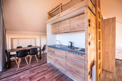 a tiny house with a kitchen and a loft bed at ForRest Glamping in Banská Štiavnica