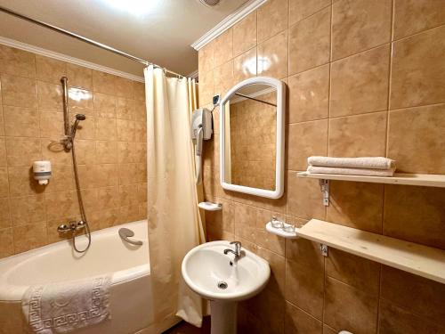 a bathroom with a sink and a bath tub and a mirror at Čill easy in Ādaži