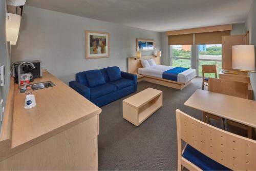 Una sala de estar con un sofá azul y una cama. en City Express by Marriott Puebla FINSA, en Puebla