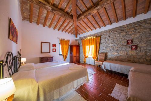 sypialnia z 2 łóżkami i kamienną ścianą w obiekcie Agriturismo il Palagetto w mieście Pomarance