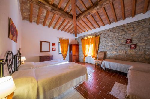 1 dormitorio con 2 camas y pared de piedra en Agriturismo il Palagetto, en Pomarance