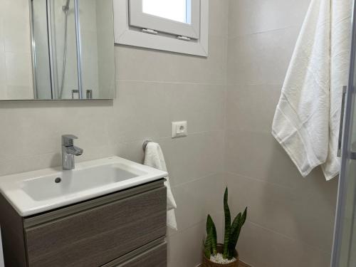 La salle de bains blanche est pourvue d'un lavabo et d'un miroir. dans l'établissement Ático By Marea Urban, à La Laguna