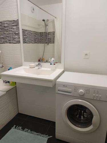 une salle de bain blanche avec une machine à laver et un lavabo dans l'établissement Stade de France Paris, à Saint-Denis
