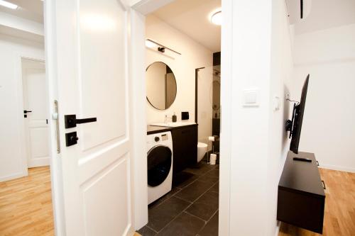baño con puerta blanca, lavadora y secadora en Apartamenty LAGOM, en Siedlce