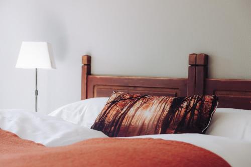 a bed with a wooden headboard and a pillow on it at Hunderfossen Hotel & Resort in Hafjell