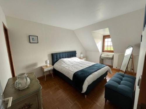 1 dormitorio con 1 cama y 1 silla azul en LA BRUVÉCA Octeville s/Mer, en Octeville-sur-Mer