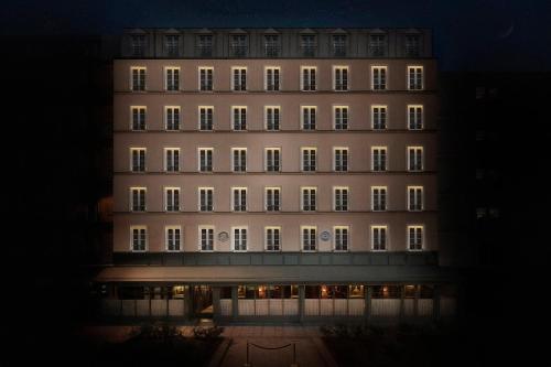 un grand bâtiment avec ses lumières allumées la nuit dans l'établissement Maison Proust, Hotel & Spa La Mer, à Paris