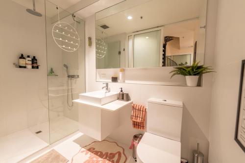 a white bathroom with a sink and a shower at Loft on Collins/Swanston - 2 storey - 2 bed 2 bath in Melbourne