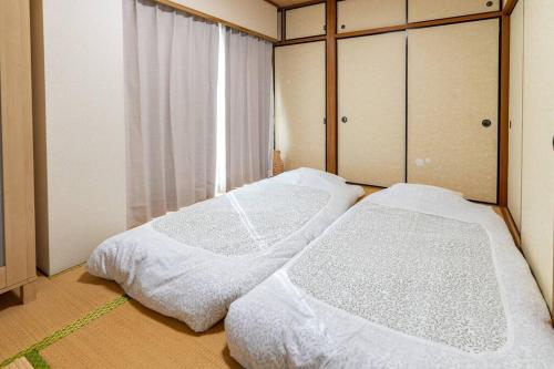 two beds sitting in a room with a window at 401号室貸切！2DK/京成佐倉駅徒歩3分・電車成田空港20分・京成上野直結！厨房/風呂/畳/4名 in Sakura