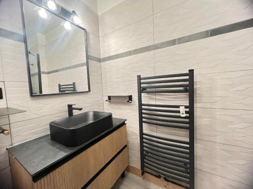 La salle de bains est pourvue d'un lavabo noir et d'un miroir. dans l'établissement Rose de Noel 145 - Proche pistes de ski, au calme, à La Clusaz
