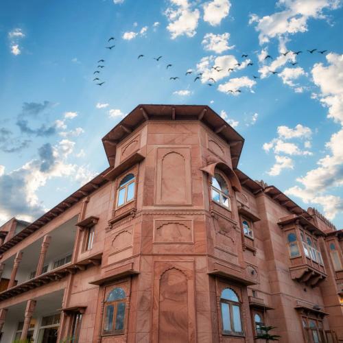 a tall brick building with birds in the sky at Castle Oodeypore A Boutique stay Udaipur in Udaipur
