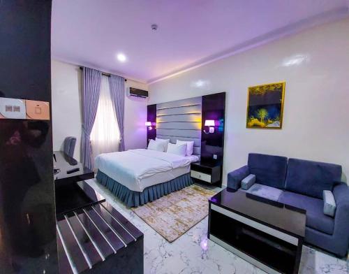Chillers Hotel and Suites في Aiyetoto-Asogun: غرفه فندقيه بسرير واريكه