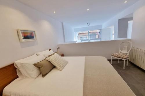 um quarto com uma grande cama branca e uma cadeira em Loft Filipinas Vibes Coruña em La Coruña