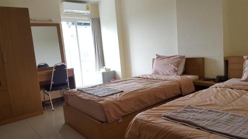 um quarto com 2 camas, uma secretária e um espelho em Good Morning Apartment em Ban Bang Khan