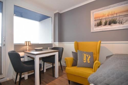 um quarto com uma cama, uma mesa e uma cadeira amarela em Haus am Meer, Whg 154, Landseite em Westerland