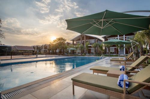 a swimming pool with two chairs and an umbrella at Spree Resort Sariska in Thāna Ghāzi