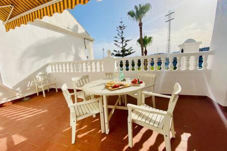 een witte patio met een tafel en stoelen bij Apartamento con piscina en Las Rosas de Capistrano in Nerja