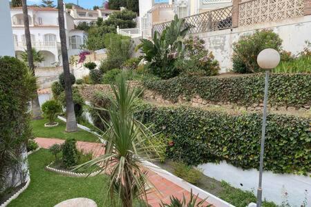 een luchtzicht op een tuin met palmbomen en een gebouw bij Apartamento con piscina en Las Rosas de Capistrano in Nerja