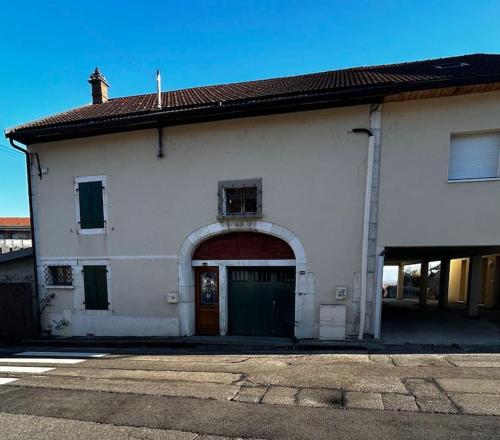 a white building with an archway and a garage at La Terrasse du Salève in Péron