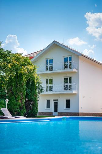 a house with a swimming pool in front of a building at Aranyszarvas Panzió****, Étterem és Grillterasz in Szarvas