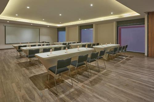 a conference room with tables and chairs and a screen at City Express Plus by Marriott San Luis Potosi in San Luis Potosí