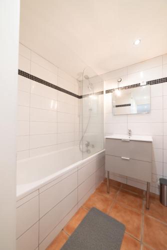 une salle de bain blanche avec une baignoire et un lavabo dans l'établissement Appartement Gardhenn Stadium LCLD Arena Groupama Lyon, à Meyzieu