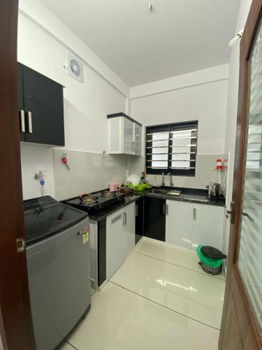 a kitchen with white cabinets and black appliances at Kandamangalath Affinity in Ernakulam