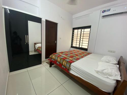 a small bedroom with a bed and a window at Kandamangalath Affinity in Ernakulam