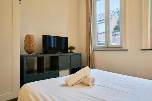 - une chambre avec une télévision et un lit avec une serviette dans l'établissement Lille Centre - Large functional studio, à Lille