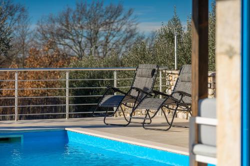 two chairs sitting on a deck next to a swimming pool at Rustic villa casa Nadalina with pool in Visnjan in Radovani
