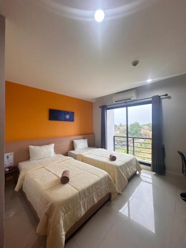 two beds in a room with a large window at I Hotel Khonkaen in Khon Kaen