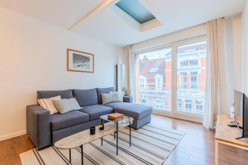 un salon avec un canapé et une grande fenêtre dans l'établissement 3 bedroom apartment with parking & balconies, à La Madeleine