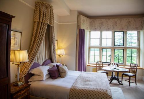 a bedroom with a bed and a table and a window at Llangoed Hall in Bronllys