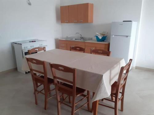 cocina con mesa, sillas y nevera en La Difisola en Lizzano