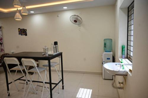 una cocina con mesa negra, sillas y fregadero en RR Enclave - service apartments en Hyderabad