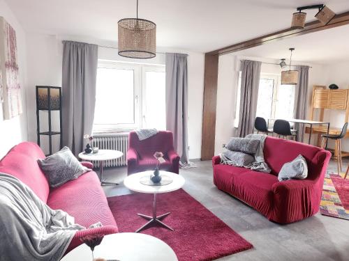 a living room with two red couches and a table at Gästehaus Senger in Bestwig