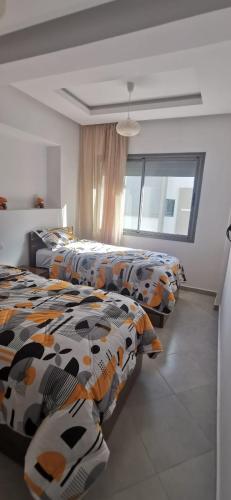 een slaapkamer met 3 bedden en een groot raam bij اقامة مفتاح الساحل in Agadir