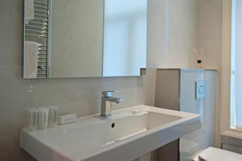 a white bathroom with a sink and a mirror at Amsterdam Rembrandt Square city center Hotel in Amsterdam