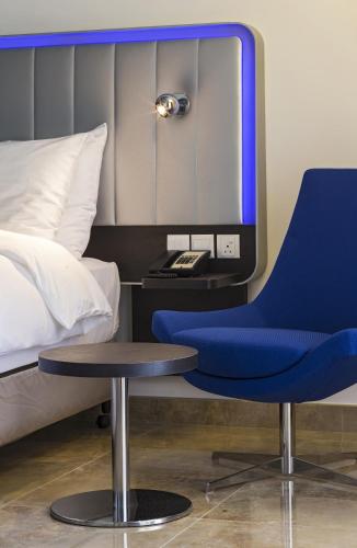 a blue chair next to a bed with a mirror at Park Inn by Radisson Hotel and Residence Duqm in Duqm