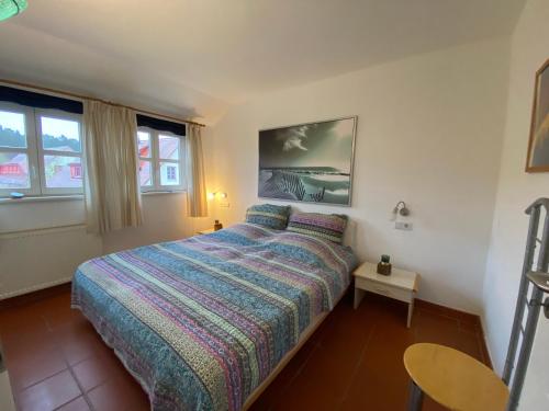 a bedroom with a bed and a table and windows at Gemütliches Apartment in Strandnähe in Dranske