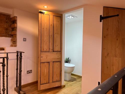 a bathroom with a toilet and a wooden door at The Forge in Towcester