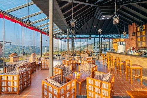 un ristorante con tavoli, sedie e finestre di Soaltee Westend Resort Nagarkot a Nagarkot