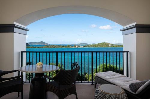 a balcony with a table and chairs and a view of the ocean at The Ritz-Carlton St. Thomas in Benner