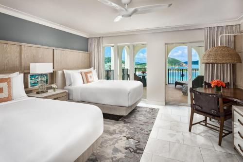 a hotel room with two beds and a desk and a television at The Ritz-Carlton St. Thomas in Benner