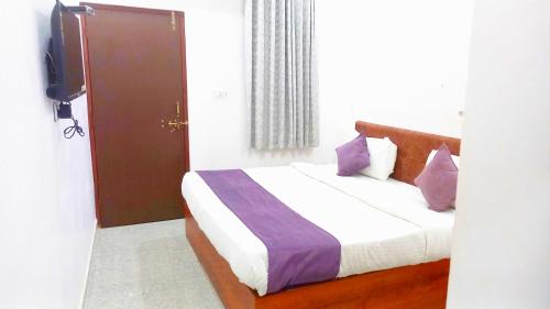 - une chambre avec un lit doté de draps blancs et d'oreillers violets dans l'établissement Hotel Mahima Palace, à Udaipur