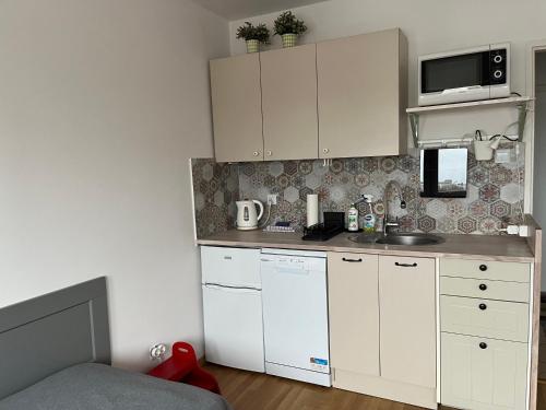 una pequeña cocina con armarios blancos y microondas en Apartament Słodowiec, en Varsovia