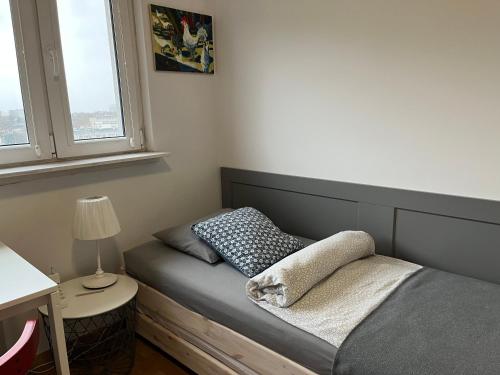 a bed in a room with a lamp and two pillows at Apartament Słodowiec in Warsaw