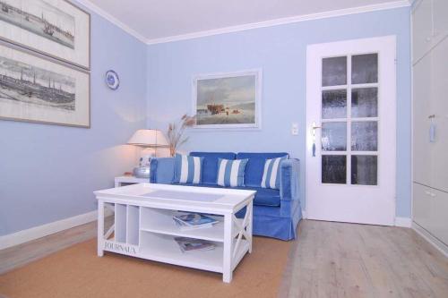 uma sala de estar com um sofá azul e uma mesa em Metropol, Whg 127, Seeseite em Westerland