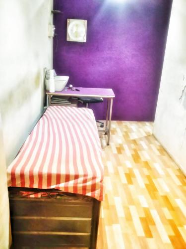a bed in a room with a purple wall at CARE DORMITORY in Mumbai