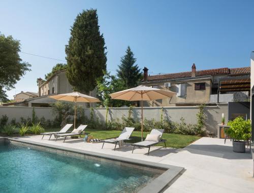 Una piscina con sillas y sombrillas al lado de una casa. en Modern villa Bino&Marija with pool in Porec, en Kirmenjak